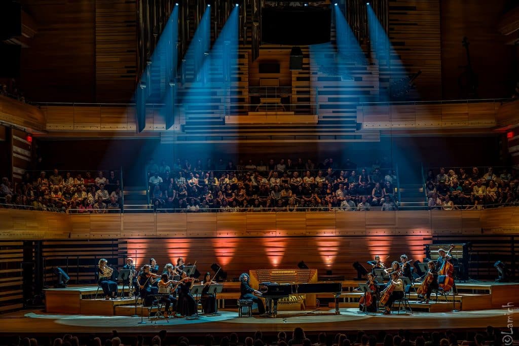 A pianist and an orchestra play centre stage.